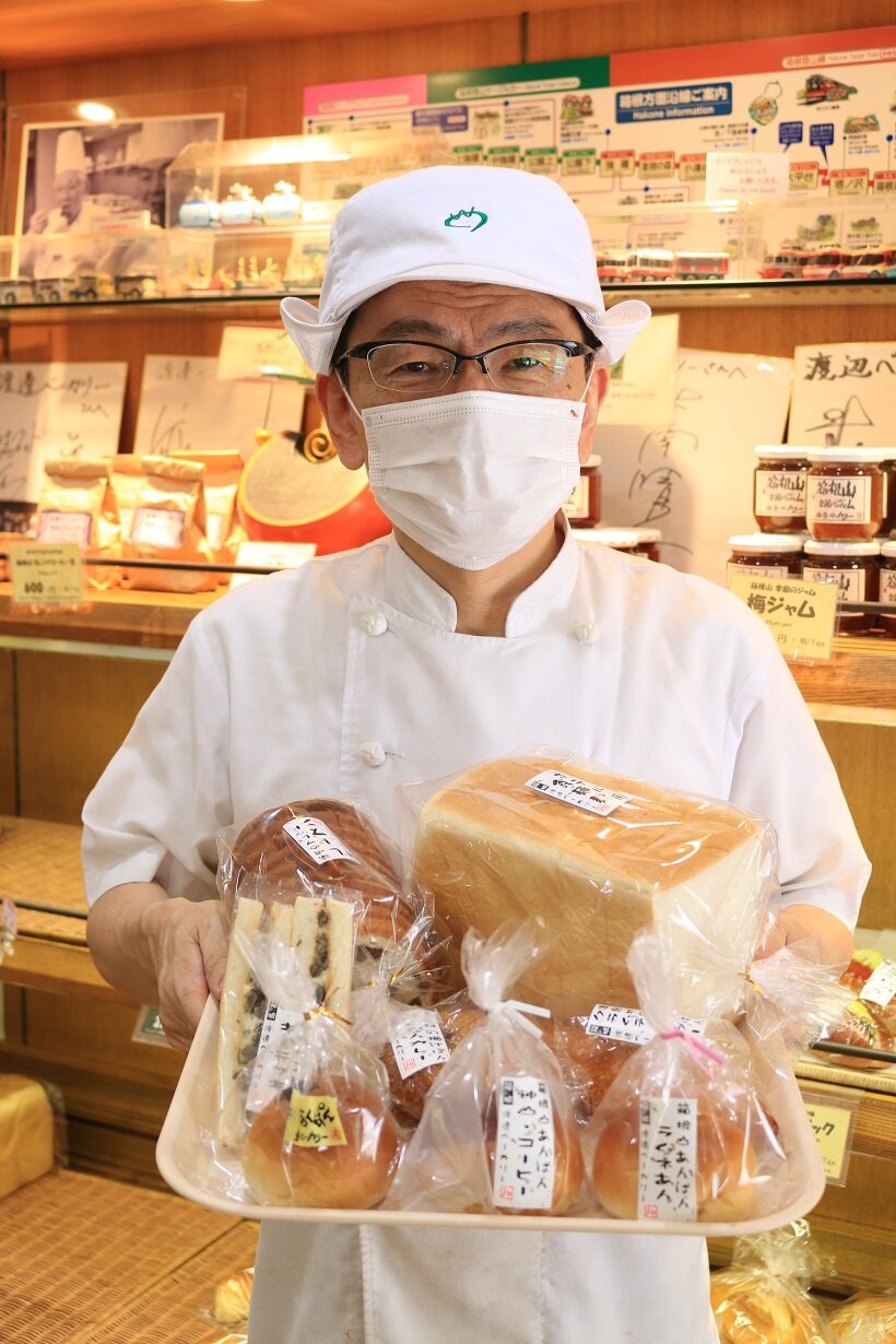 自慢のパンを手にする5代目主人・渡邊貞明さん